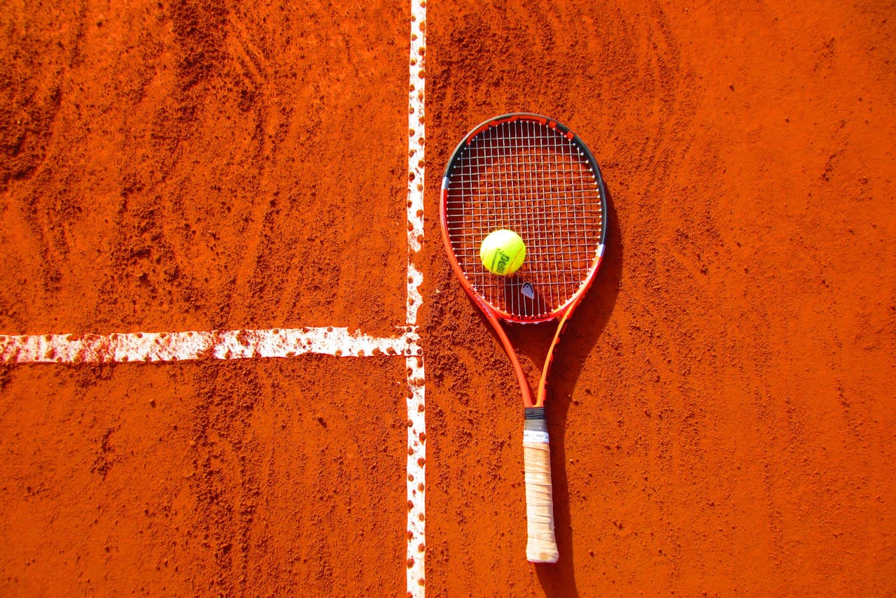 Mastering the First Impression: Your intriguing post title goes here Tennis racket and ball on red clay court, ideal for sports-themed content.